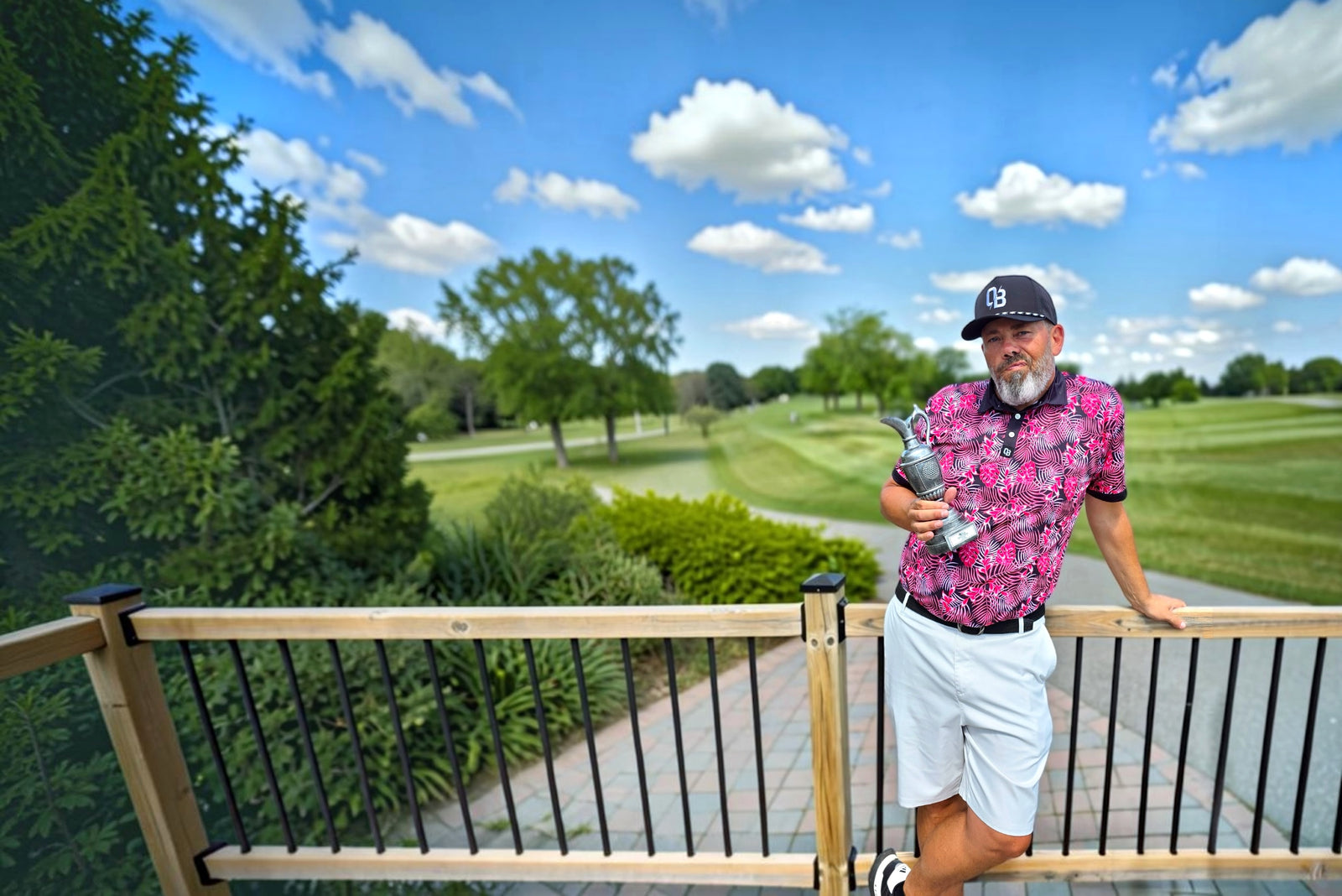 Golfer wearing a pink Shop Out of Bounds polo and holding a golf trophy