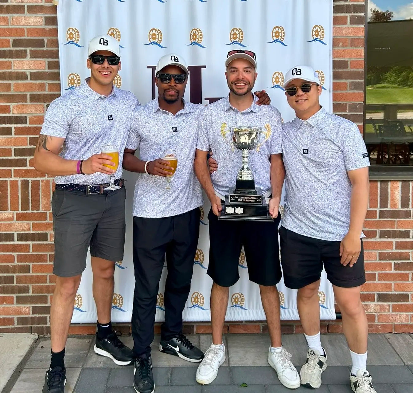 Four-person golf tournament team wearing matching Shop Out of Bounds polos and hats