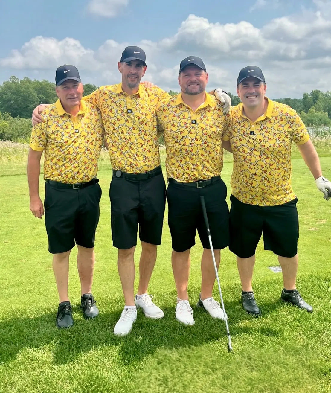 Four golfers wearing matching yellow Shop Out of Bounds polos on the course